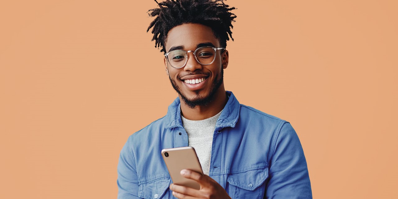 Ein Mann mit Bart und Brille schaut zufrieden auf sein Smartphone - NettoKOM