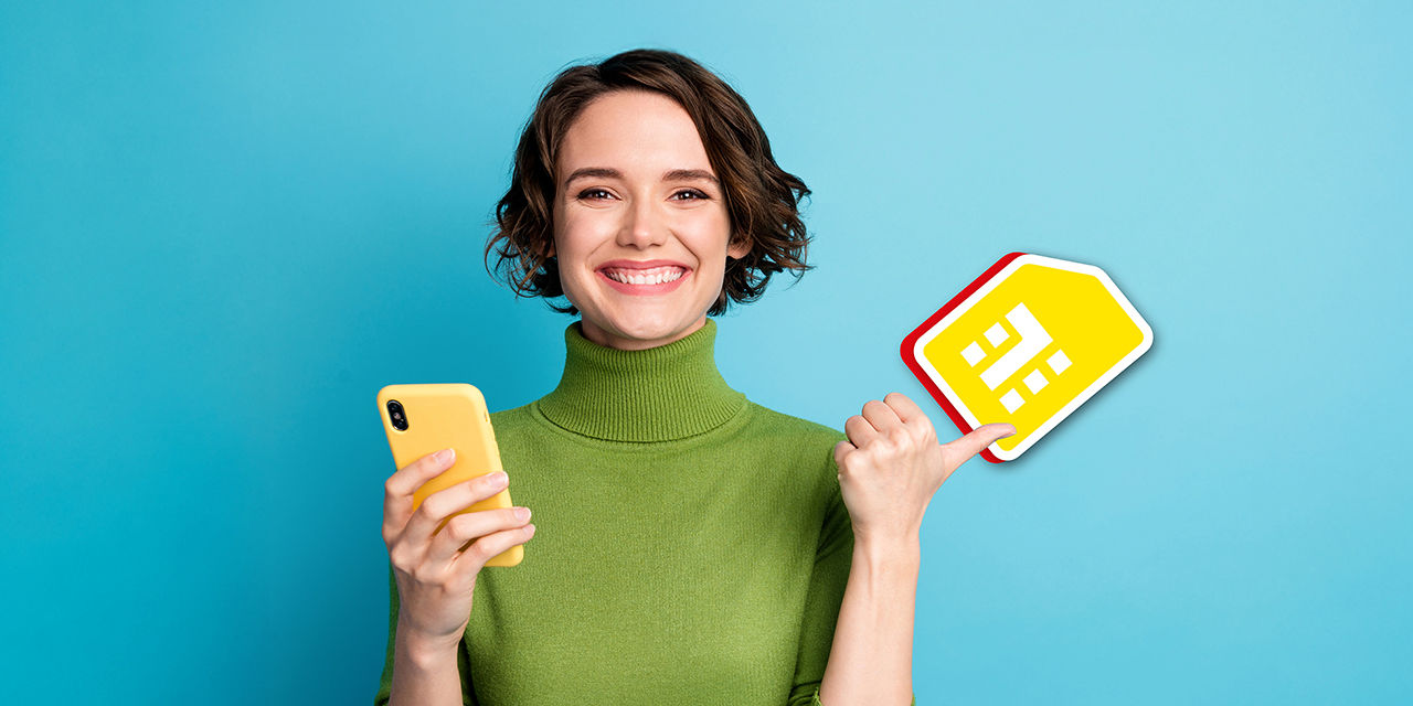 Junge Frau hält ein Smartphone in der Hand und zeigt lächelnd auf ein gelbes SIM-Karten-Symbol.