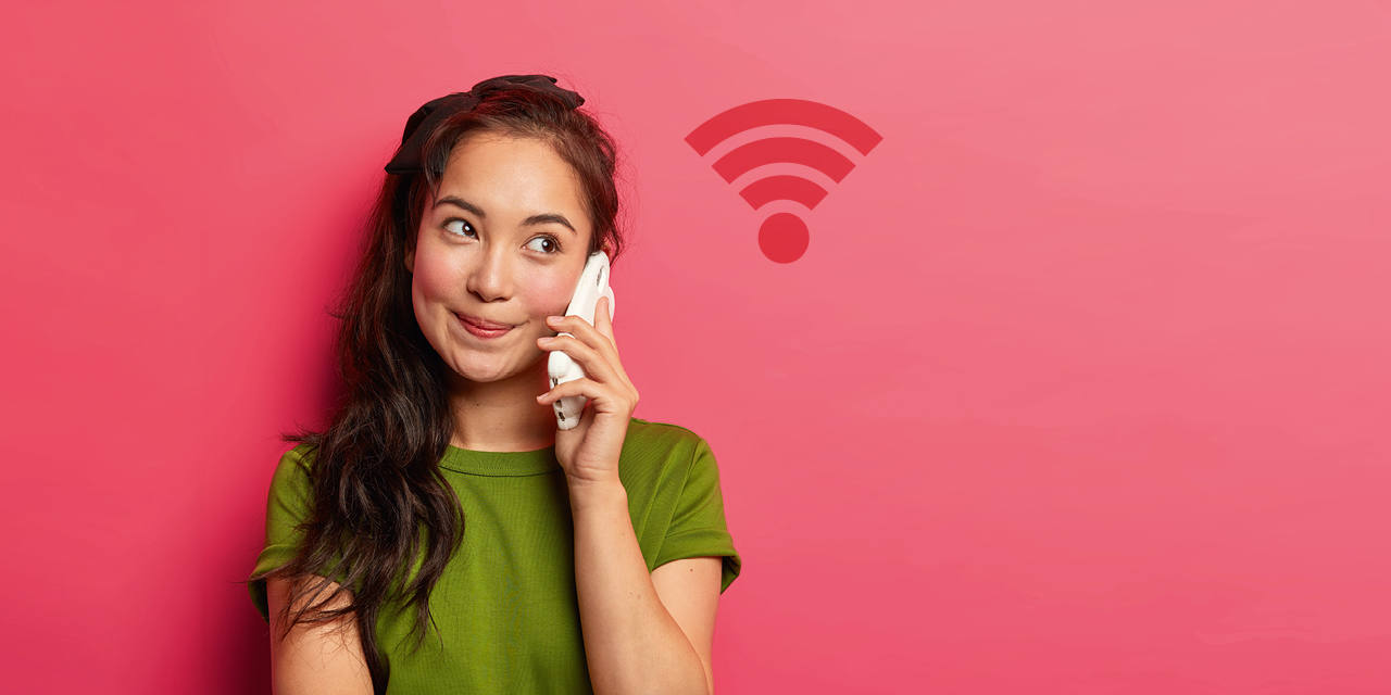 Frau telefoniert mit einem Smartphone, daneben ist ein WLAN-Symbol zu sehen.