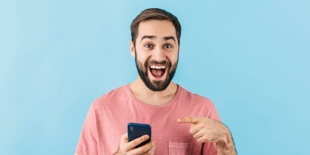 Mann mit Smartphone in der Hand reagiert freudig erstaunt.